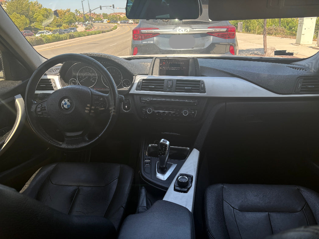 Car interior with dashboard and steering wheel, showing a view of the road through the windshield.