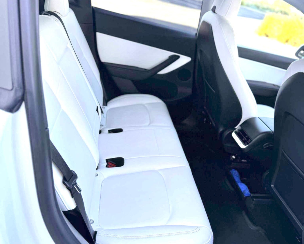 Car interior with white seat covers and visible car brand logo.