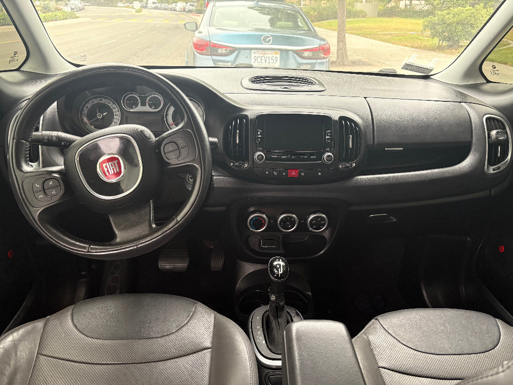 Car interior with steering wheel and dashboard, showing a Fiat logo.