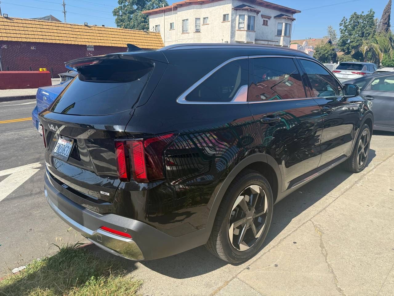 Black SUV for rent parked on San Diego street with buildings and trees in the background