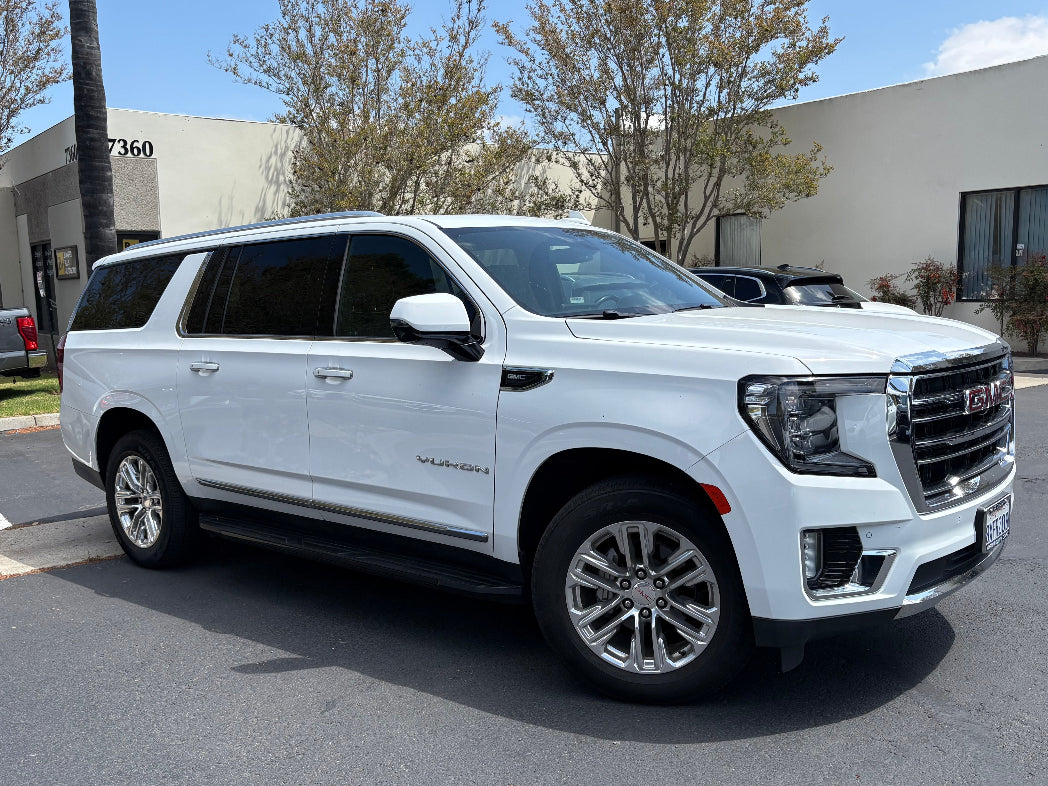 Side profile of full-size white GMC Yukon SUV for rent