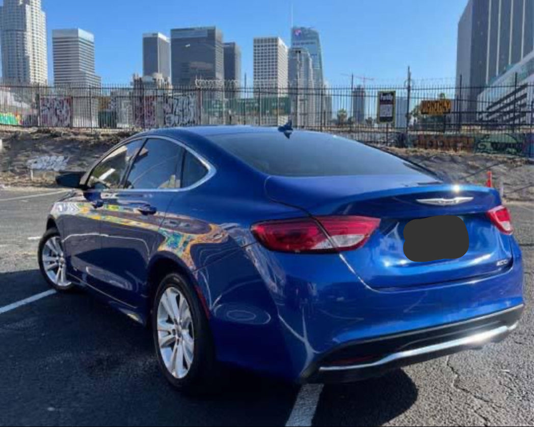 Blue car parked in a lot with city skyline in the background