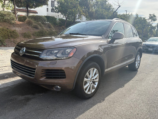 Brown Volkswagen SUV parked on a street with trees and buildings in the background