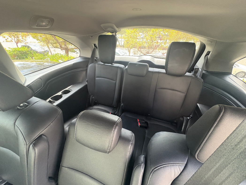 Backseat view of a car interior with gray seats and windows showing outdoor scenery.