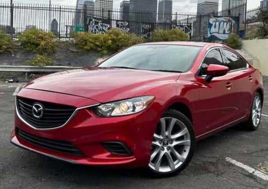 Red Mazda car parked on a street with a cityscape background
