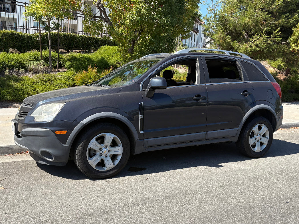 Gray SUV parked on a street with trees and buildings in the background