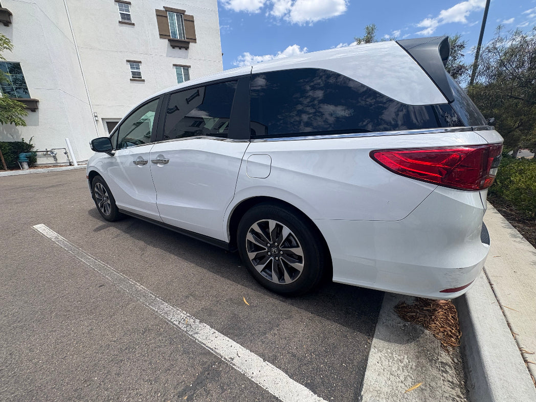 White minivan parked on a street with buildings in the background