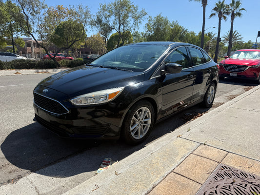 Black Ford car parked on a street with palm trees and other cars in the background