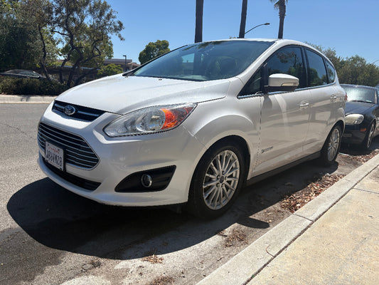 White Ford car parked on a street with trees and buildings in the background