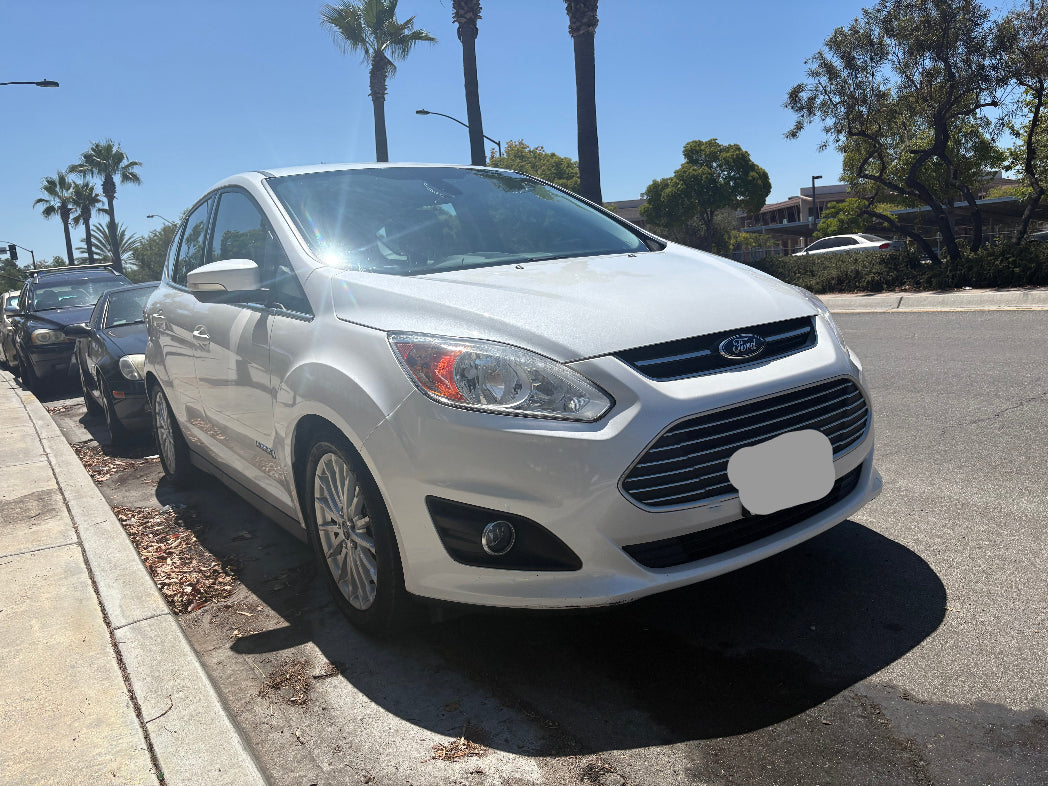 White Ford car parked on a street with palm trees in the background