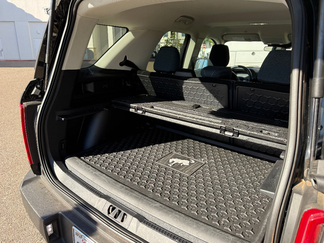 Open car trunk with a cargo mat featuring a logo on a concrete surface.