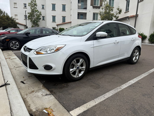 White car parked on a street with buildings in the background