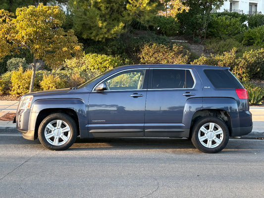 Blue SUV parked on a street with trees and buildings in the background