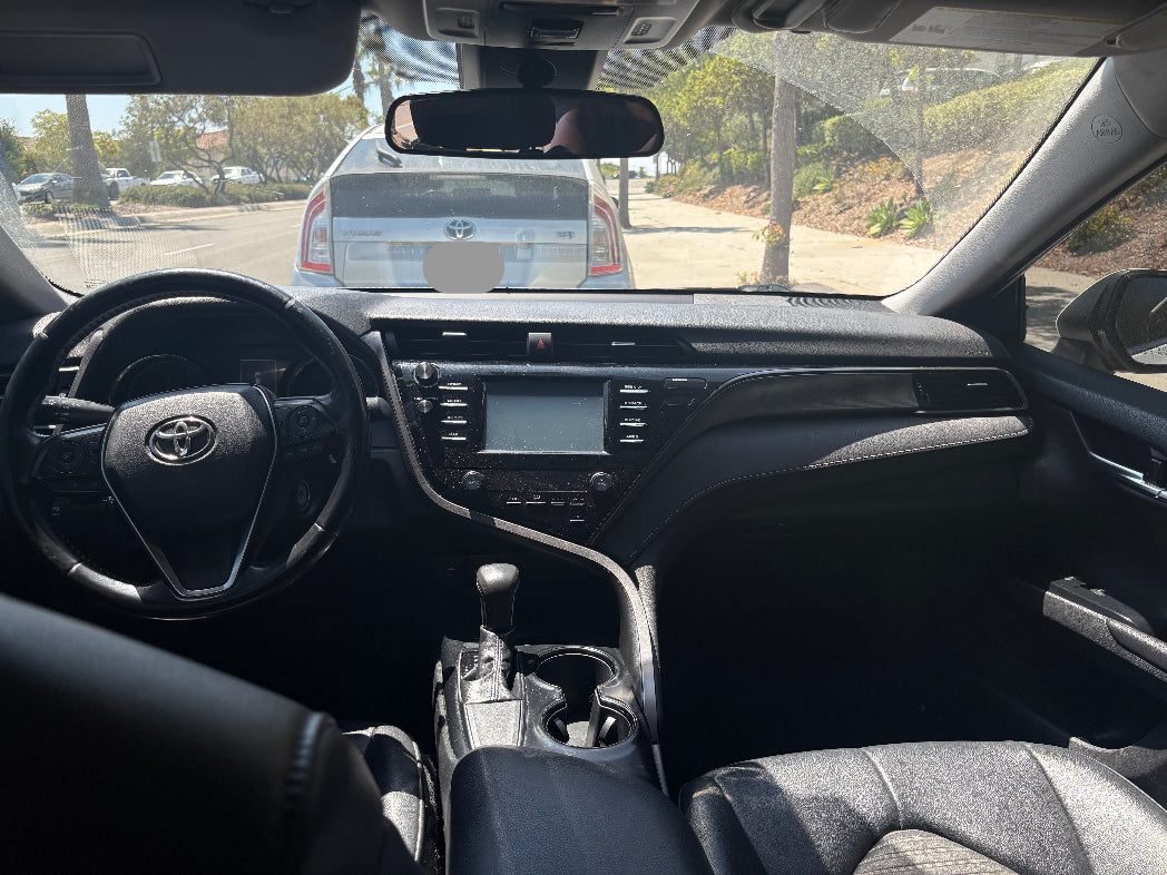 Car interior with dashboard and steering wheel, showing a Toyota logo.