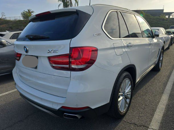 White BMW X5 SUV parked in a lot with visible license plate