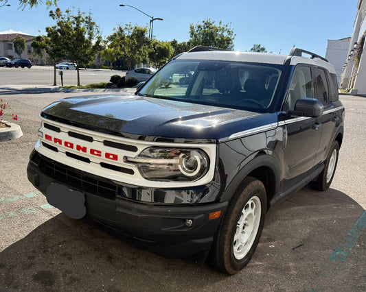 Ford Bronco SUV for rent in san diego parked in a parking lot with trees and buildings in the background.