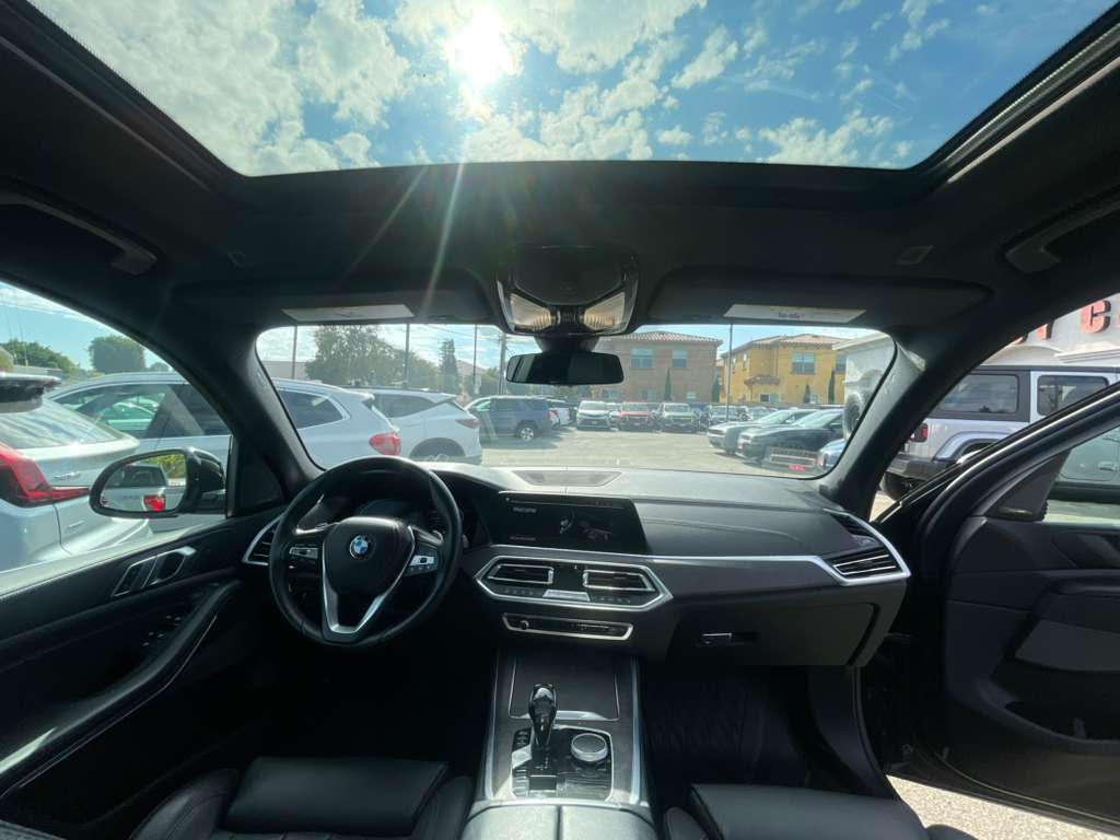 Car interior with a view of a parking lot through the windshield.