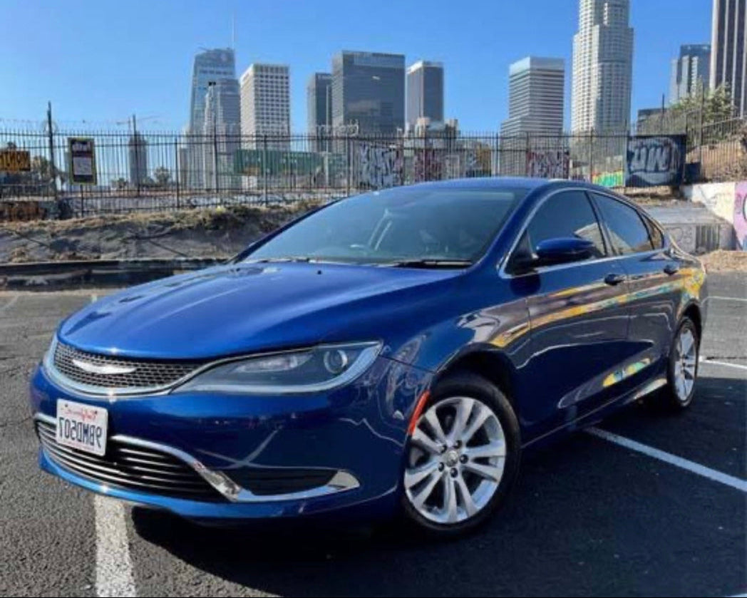 Blue car parked in a lot with city skyline in the background