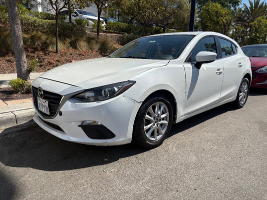 White Mazda for rent in San Diego parked on a street with trees and other cars in the background