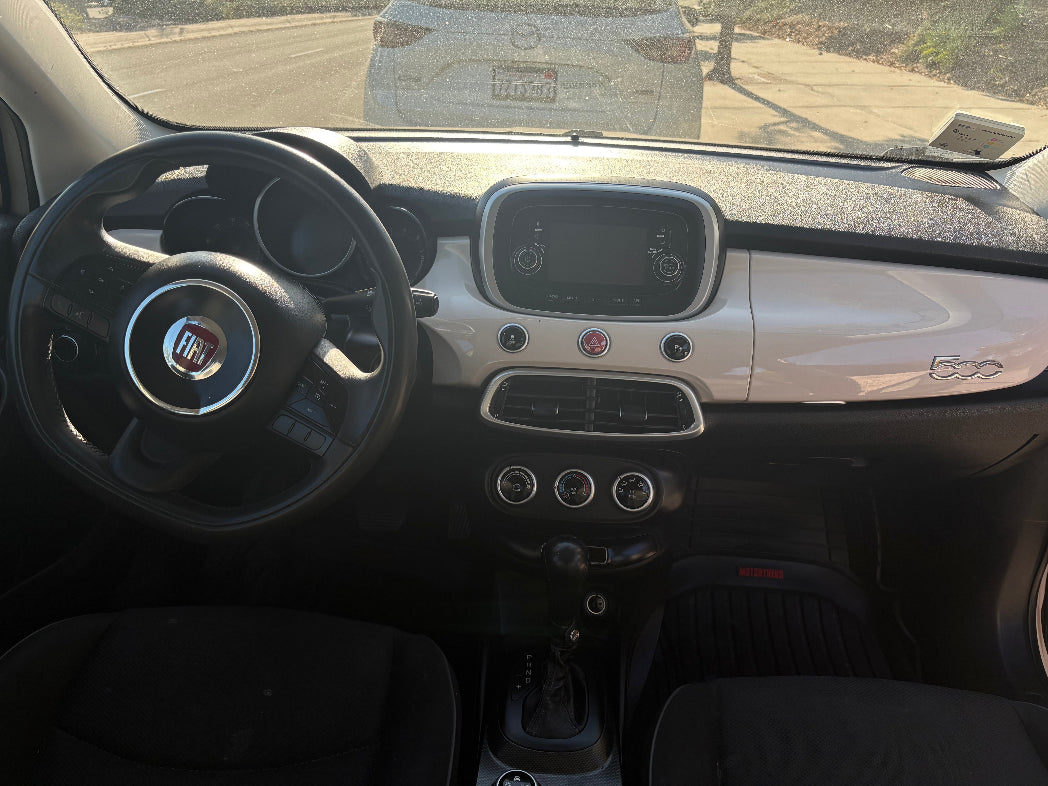 Car interior with steering wheel and dashboard, showing a clear view of the Fiat logo.