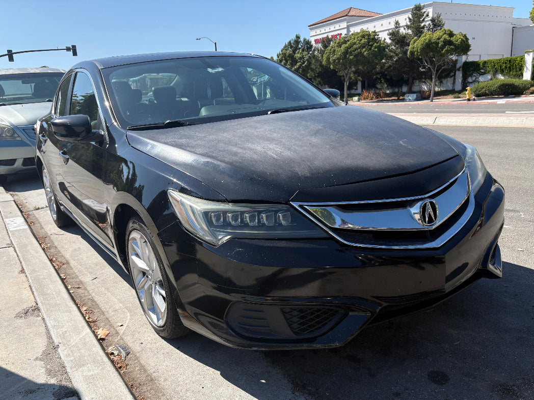 Black Acura car parked on a street with trees and buildings in the background