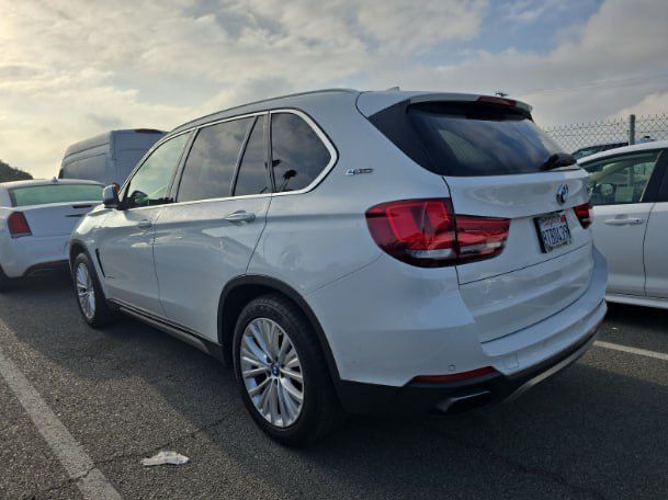 White BMW SUV parked on a road with a cloudy sky in the background
