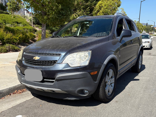 Gray Chevrolet SUV parked on a street with trees and buildings in the background