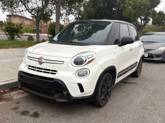 White Fiat car parked on a street with trees and buildings in the background