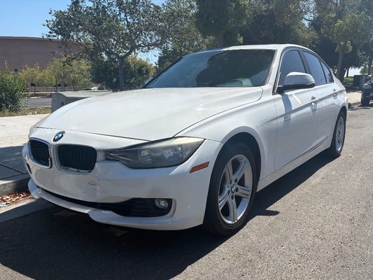 White BMW car parked on a street with trees in the background