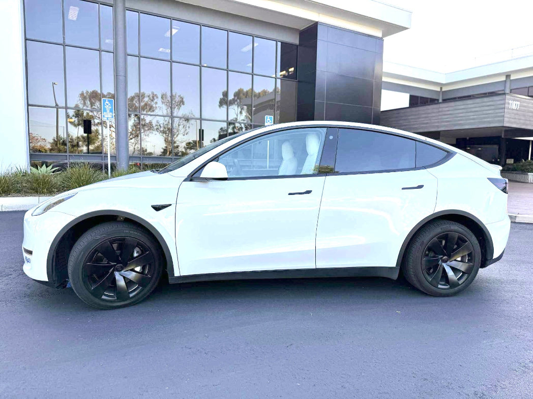 White Tesla Model Y parked in front of a modern building