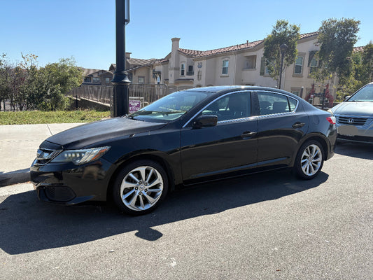 Black sedan car parked on a street with buildings in the background