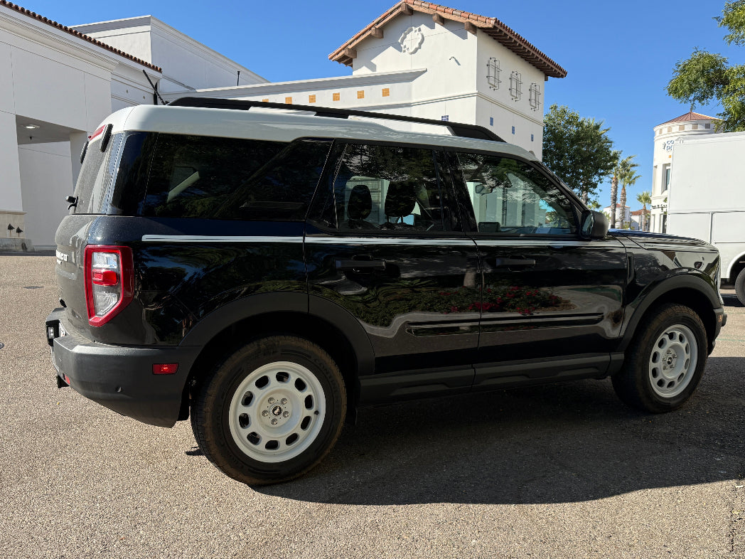 Black SUV parked on a concrete surface with buildings and trees in the background