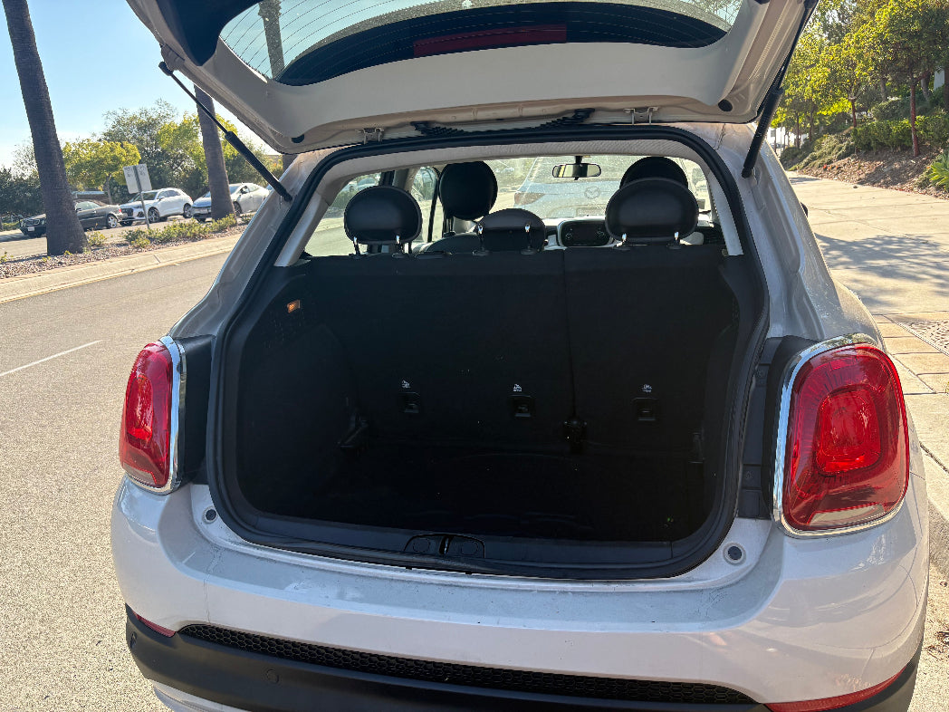 Back of a white car with open trunk in a parking lot
