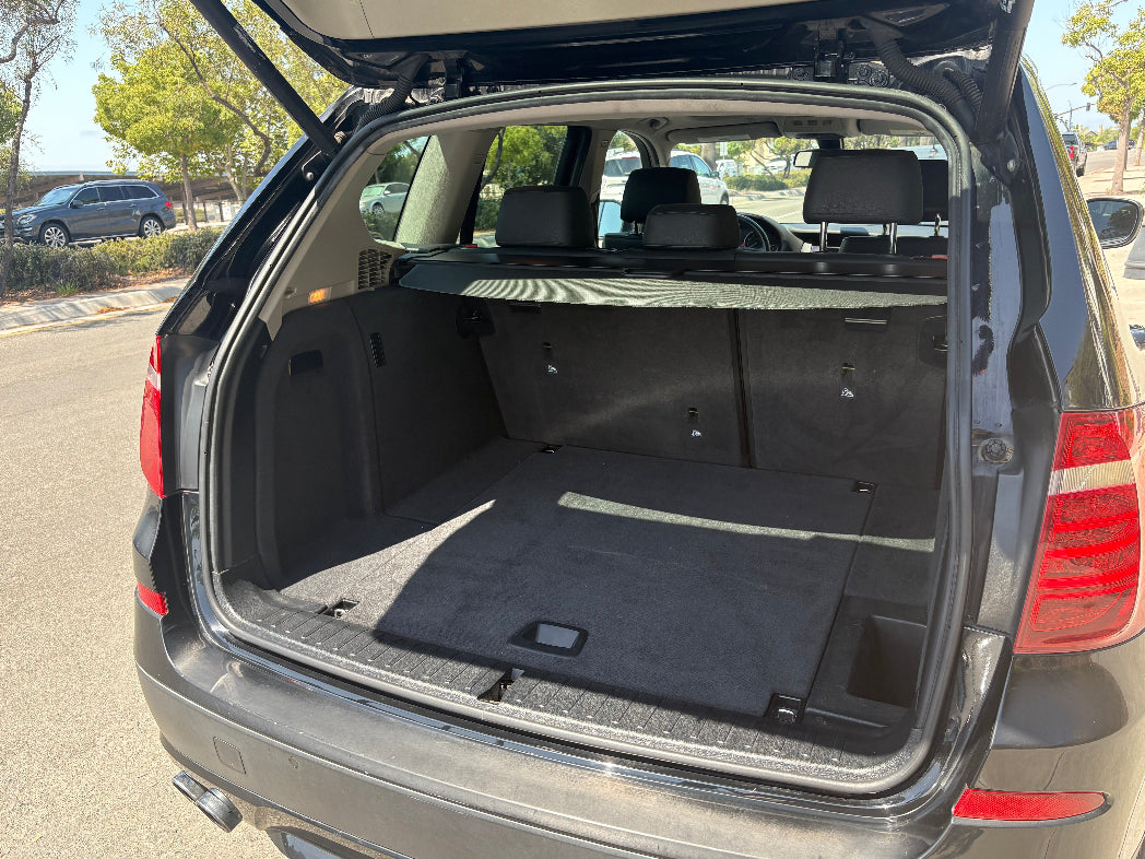 Open trunk of a car with a mat inside, parked outdoors.