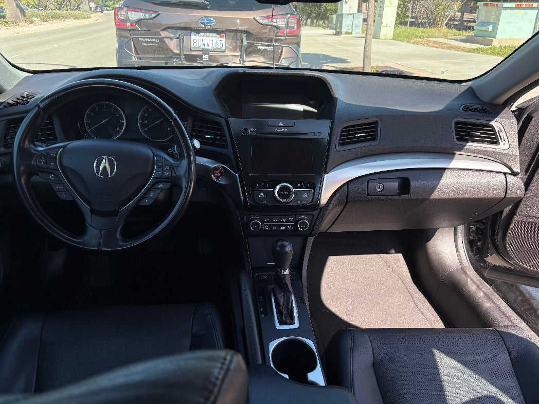 Car interior with Acura logo, dashboard, and steering wheel.