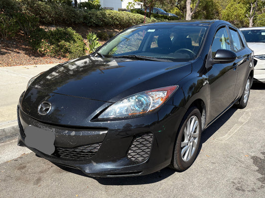 Black Mazda car parked on a street with other vehicles in the background