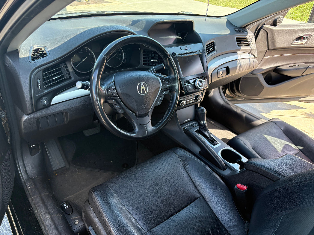 Car interior with steering wheel and dashboard, showing Acura logo.