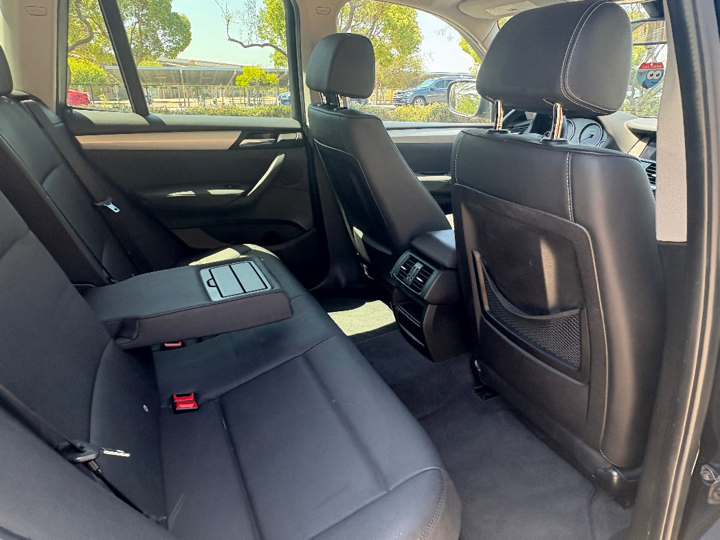 Backseat of a car with visible seat belts and window controls.