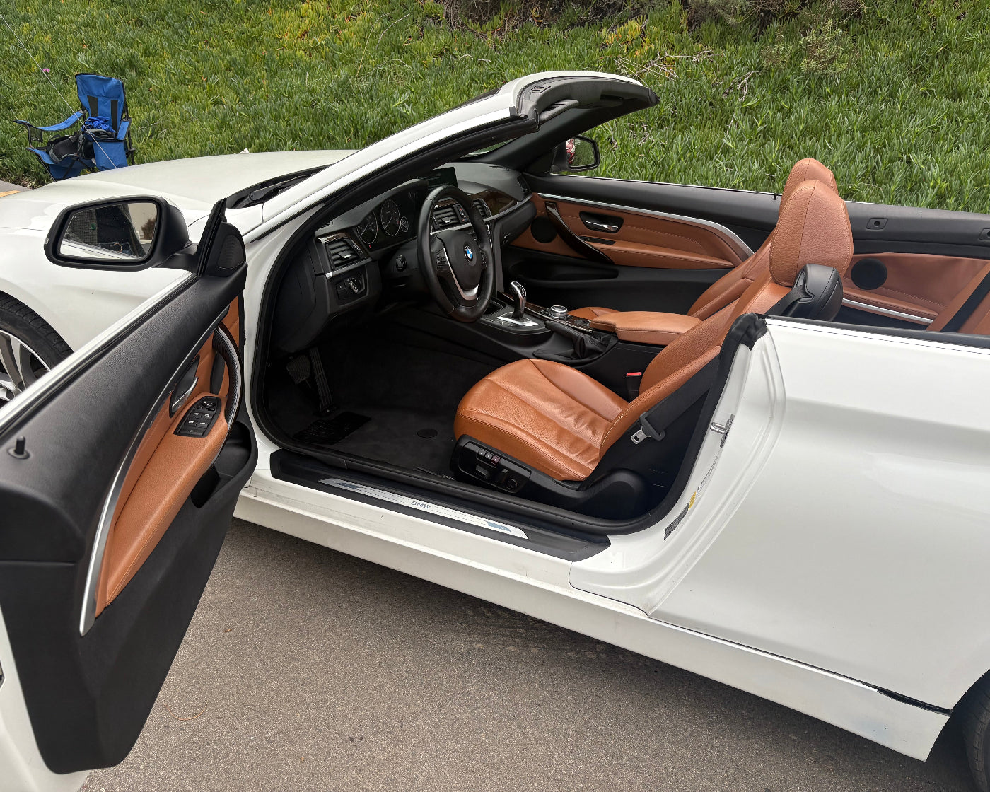White convertible car with brown interior on a road.