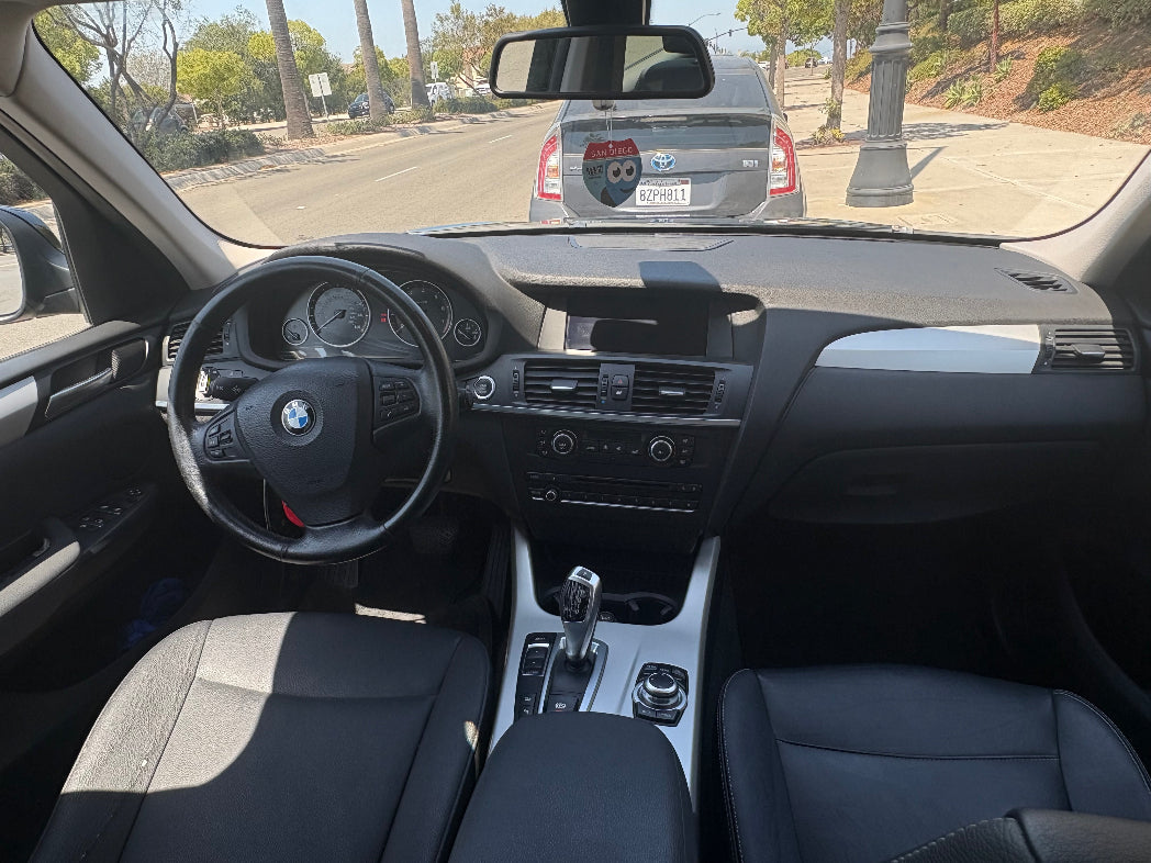 Car interior with dashboard and steering wheel, showing a BMW logo.