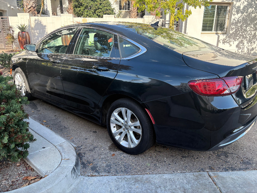 Black car parked on a driveway next to a house