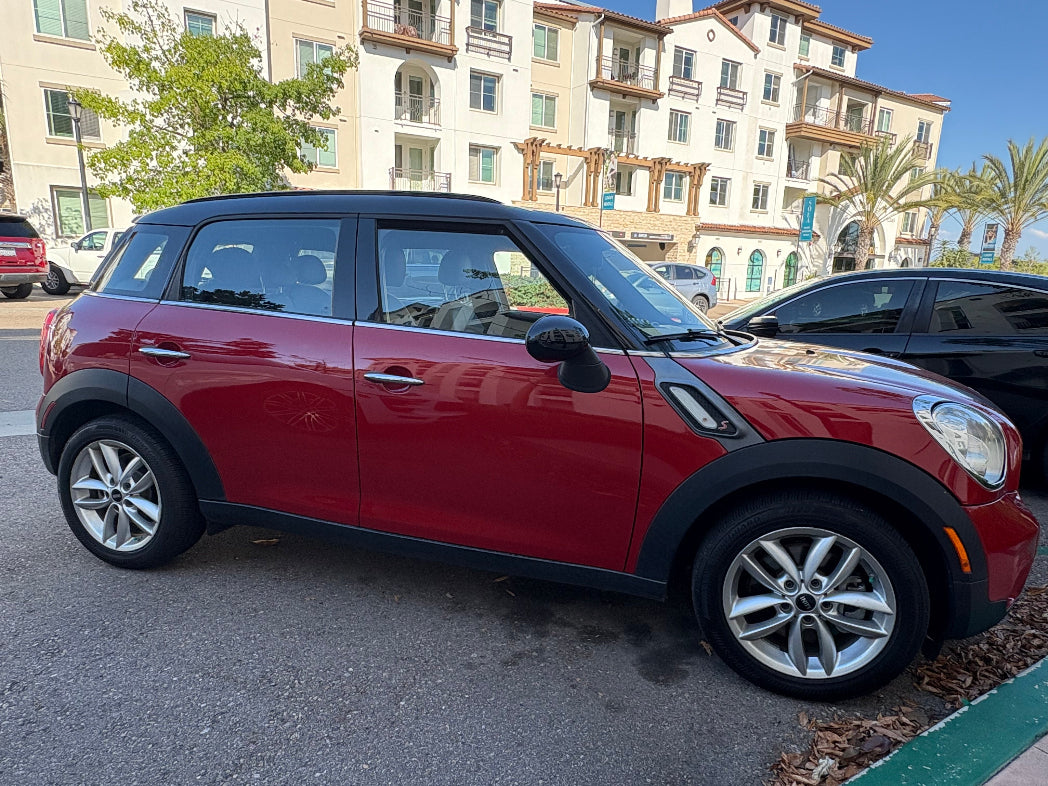 Red Mini Cooper parked in a parking lot with buildings in the background