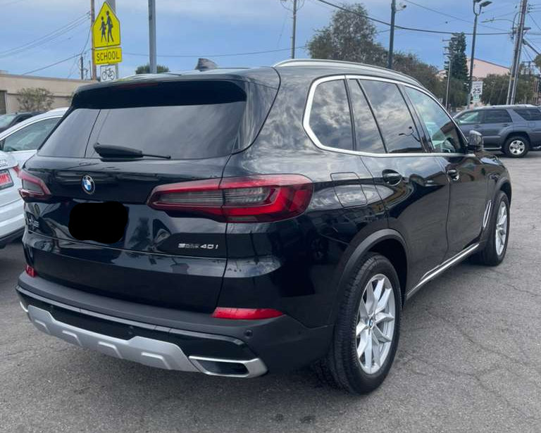 Black BMW SUV parked on a street with power lines and buildings in the background.