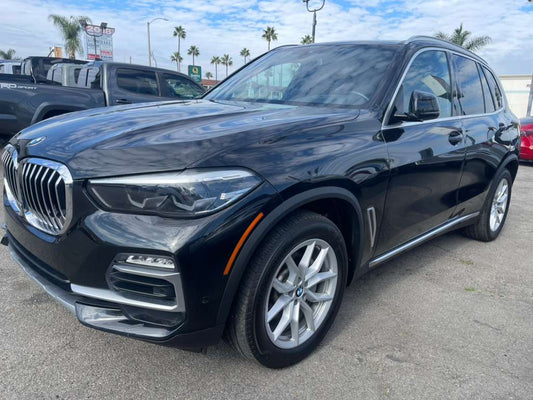 Black BMW SUV parked in a lot with palm trees in the background